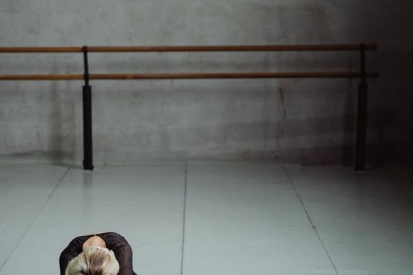 Person performing a fluid stretching movement in a minimalist studio.