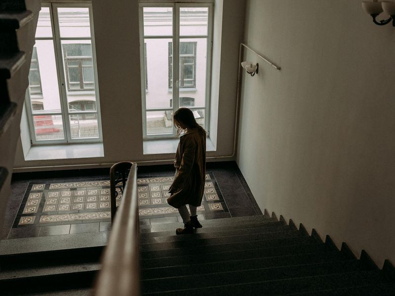 Wide shot of a person in a dynamic, flowing pose in a bright, open space.